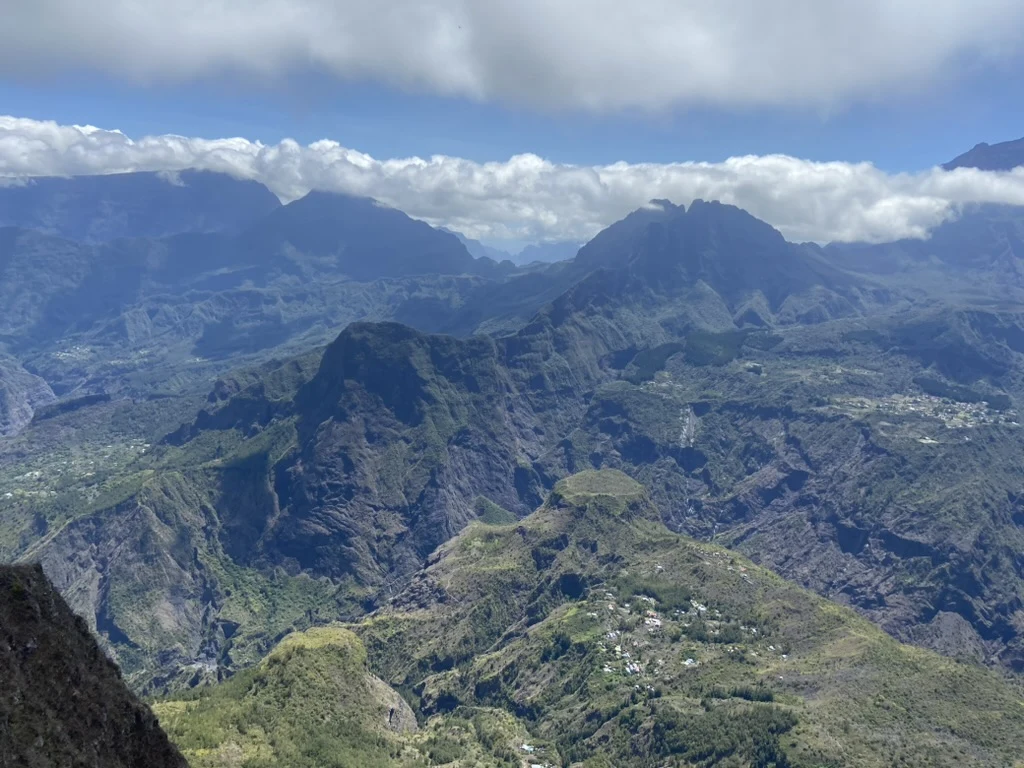 Mountain ridges and inhabited valleys on Réunion Island beneath a bank of clouds.